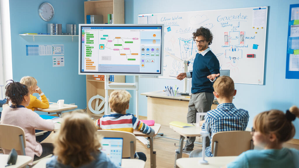 Ein Lehrer unterrichtet seine Klasse mit Hilfe eines digitalen Whiteboards.
