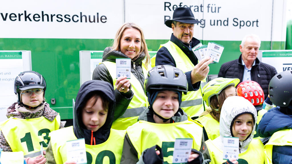 Ministerpräsident Dr. Markus Söder und Kultusministerin Anna Stolz halten zusammen mit Schülerinnen und Schülern den neuen Radlführerschein hoch